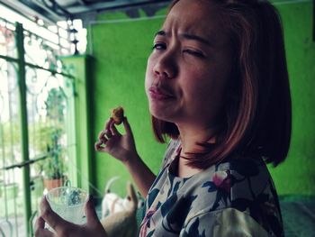 Close-up portrait of woman having food while making face at home