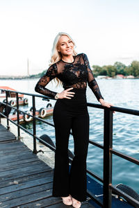 Portrait of woman standing against railing in water