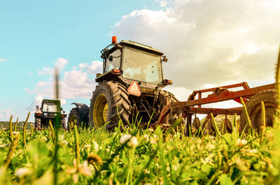 Tractors on agricultural field against sky