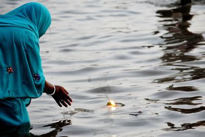 Woman standing by floating candle in river