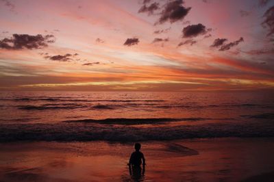 Silhouette man standing on beach against sky during sunset