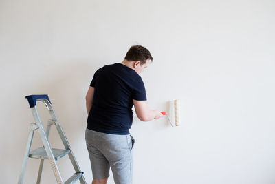 Rear view of man working on wall