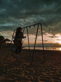 Rear view of girl on beach against sky during sunset