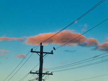 Low angle view of electricity pylon against blue sky