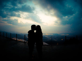 Silhouette couple standing on beach against sky during sunset