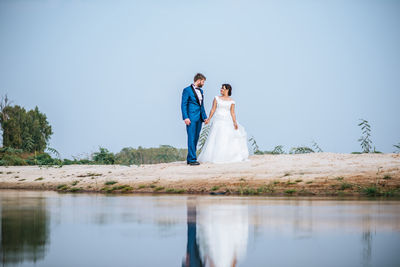 Couple holding umbrella while standing in water