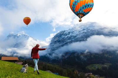 Rear view of woman with hot air balloons against sky