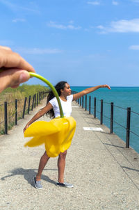 A man holds a yellow tulip upside down in front of a mixed race woman to create her skirt