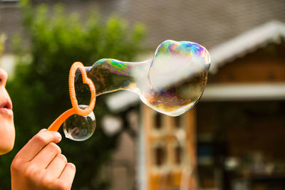 Cropped image of kid blowing bubble in back yard