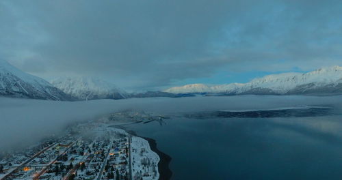 Scenic view of lake by snowcapped mountains against sky