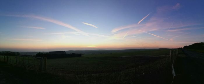 Scenic view of agricultural field against sky during sunset