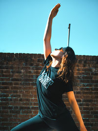 Woman with arms raised standing against wall