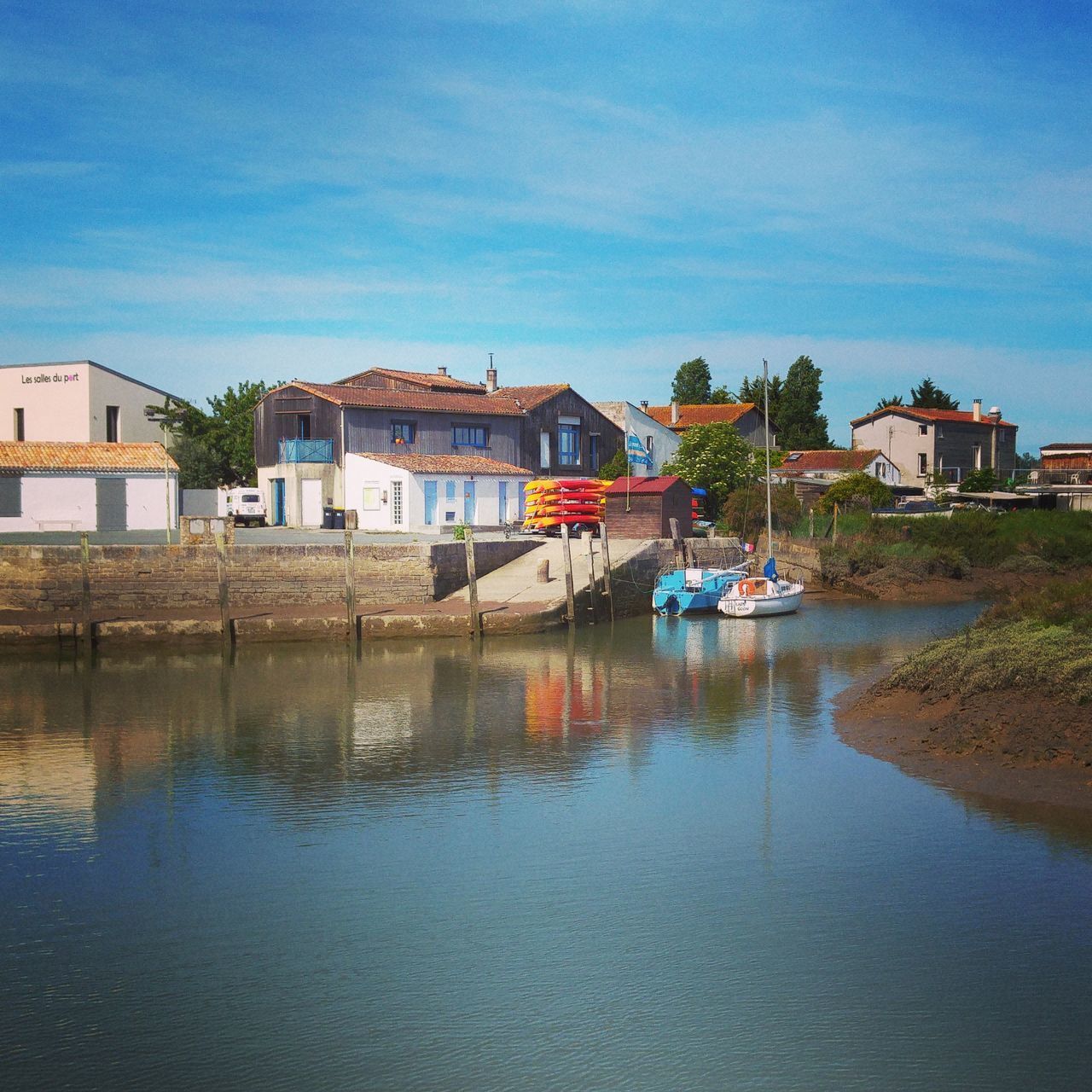 BOATS MOORED IN CANAL BY HOUSE AGAINST SKY