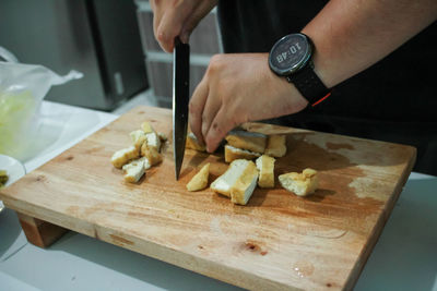 Cropped hands of man chopping food on cutting board at home