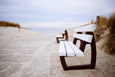 Deck chairs on beach against sky