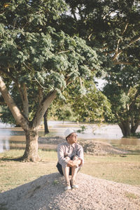 Full length portrait of a man sitting on tree