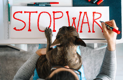 Person and french bulldog dog writing banner for anti-war rally