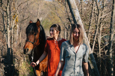 Young women with horse walking amidst trees