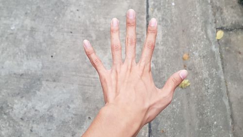 Close-up of hand gesturing at footpath