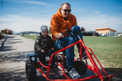 Father and son smiling having fun riding a cart in a park in winter