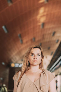 Portrait of young woman standing against ceiling