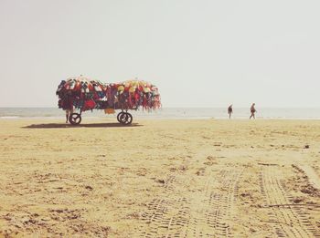 Cart with swimwear for sale at beach against sky