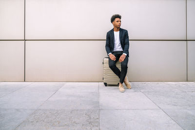 Full length portrait of young man standing against wall