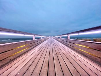 Surface level of boardwalk against blue sky