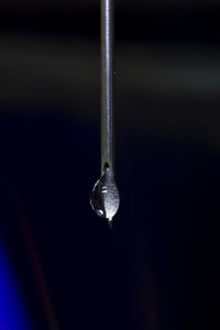 Close-up of water drop hanging from metal