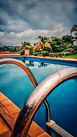 Swimming pool by lake against sky