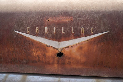 Close-up of rusty sign on wood in city