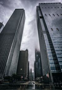 Low angle view of skyscrapers against cloudy sky