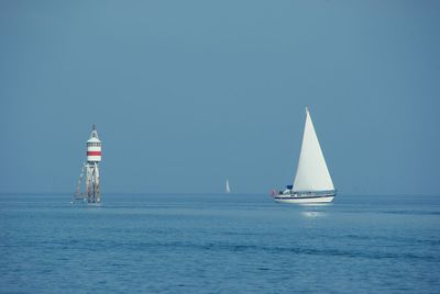 Sailboat sailing on sea against clear sky