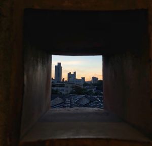 Buildings against sky seen through window