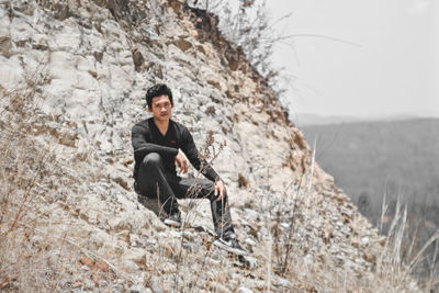 Portrait of young man sitting on rock