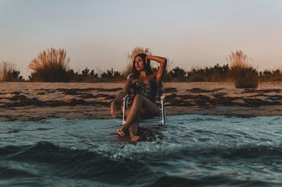 Portrait of young woman at beach against sky