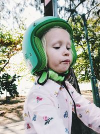 Girl wearing crash helmet against trees