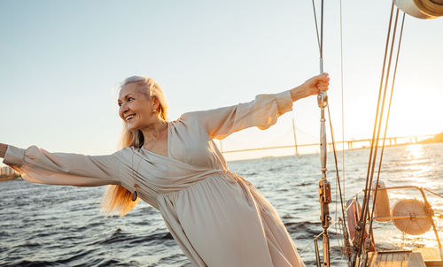 Smiling senior woman on sailboat in sea against sky