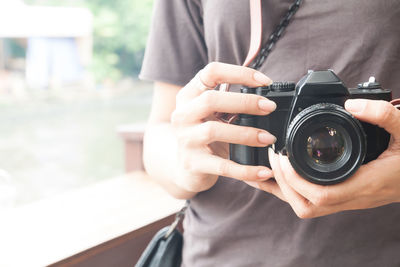 Midsection of woman holding camera 