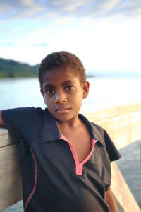 Portrait of boy standing in sea against sky