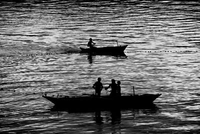 Silhouette people on boat sailing in water