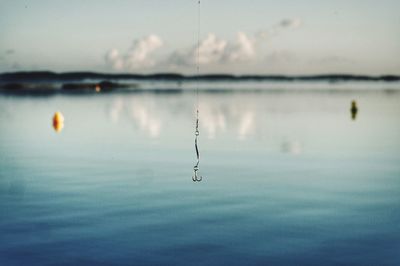 Close-up of water drop on lake against sky