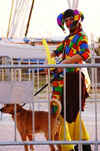 Side view of man in clown costume with dog