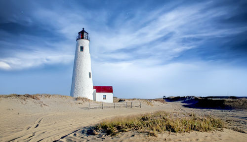 Lighthouse by sea against sky