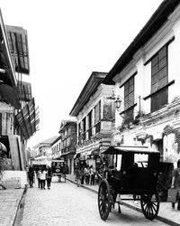 People on street amidst buildings in city against clear sky