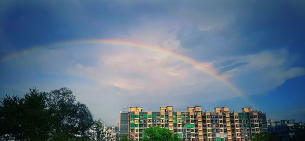 Low angle view of rainbow over buildings against sky