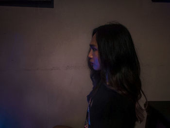 Portrait of woman standing against wall at home