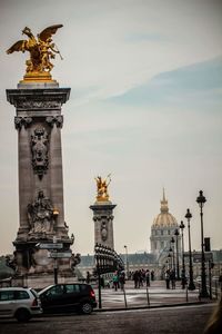 Statue in city against sky