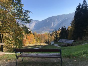 Empty bench in park against sky during autumn