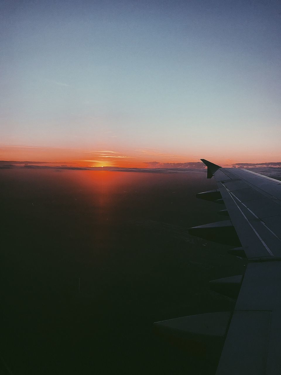 AIRPLANE FLYING OVER SEA DURING SUNSET